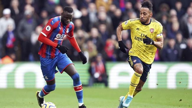 Cheikou Kouyate berupaya menggiring bola sambil dibayang-bayangi Pierre-Emerick Aubameyang. (Tess Derry/PA via AP)