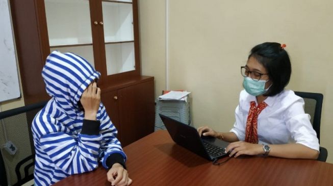 Pria berinisial RH (kiri) yang menyamar di media sosial sebagai cewek bernama `Mawar` ketika dihadirkan ke hadapan penyidik di ruang Satreskrim Polresta Mataram, NTB, Senin (8/6/2020). (ANTARA/Dhimas B.P.)